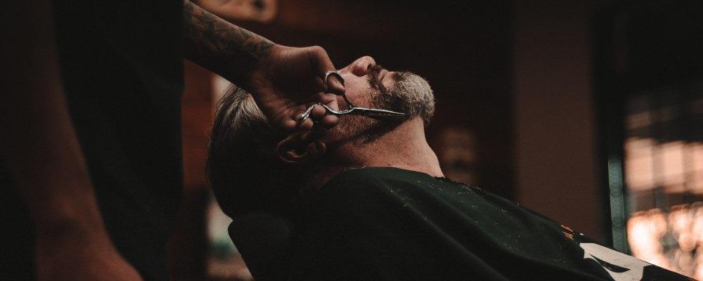 A barber trimming a beard in a barber shop