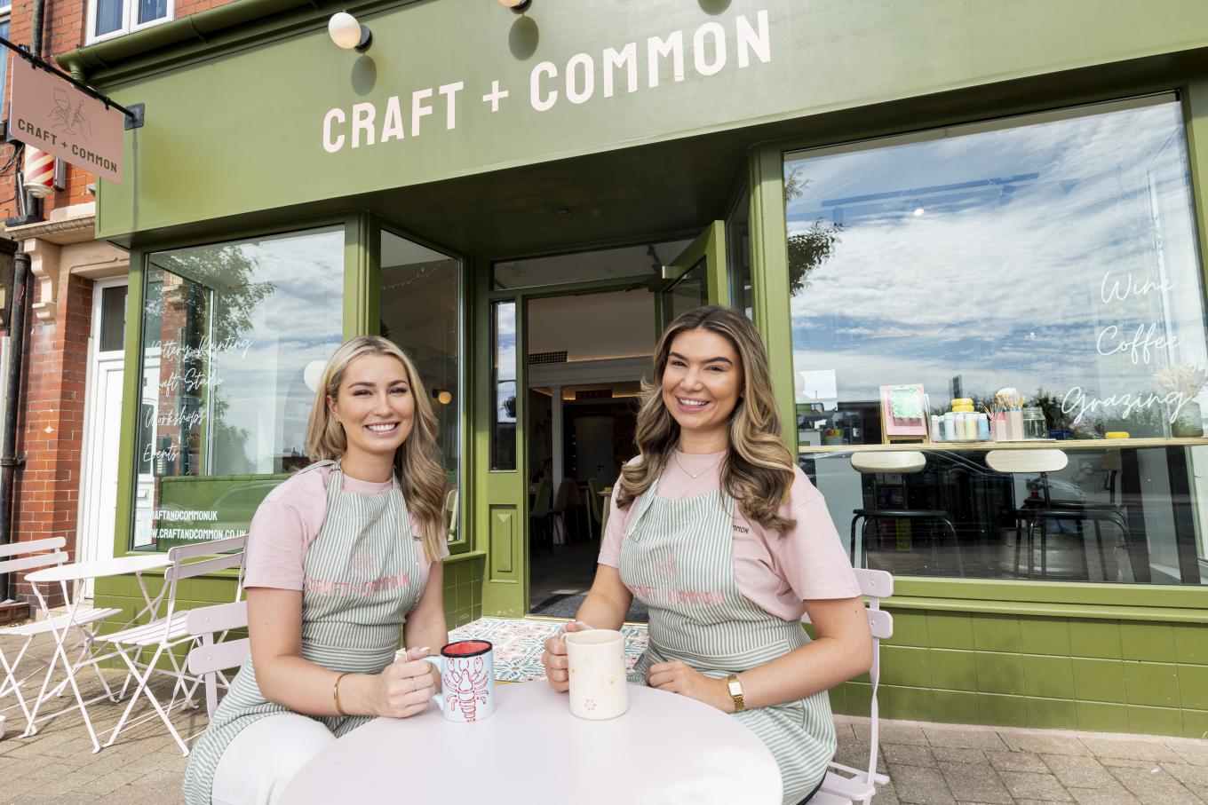 Founders of Craft +Common sitting in front of their business holding coffee mugs
