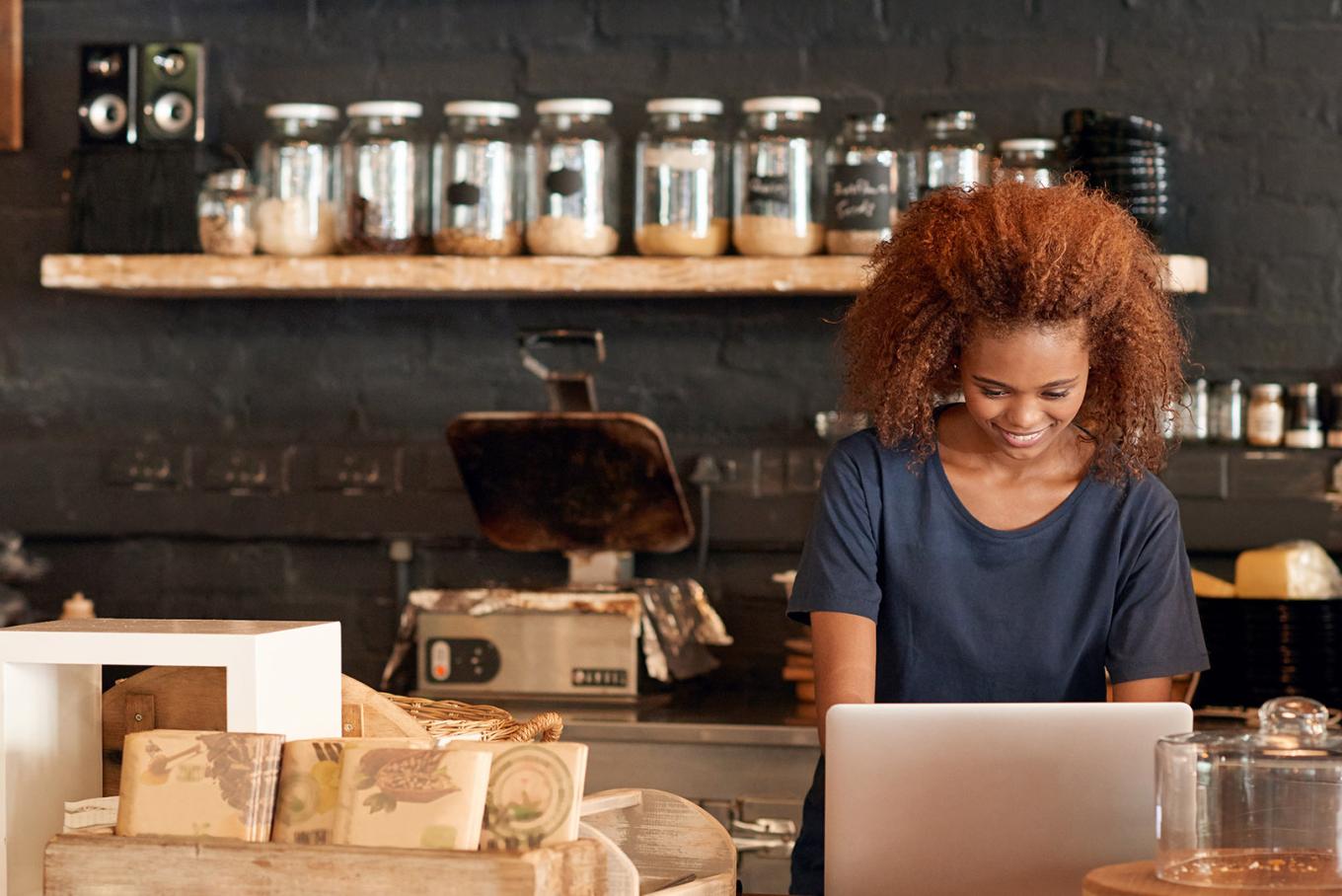 woman smiling looking at laptop in a cafe
