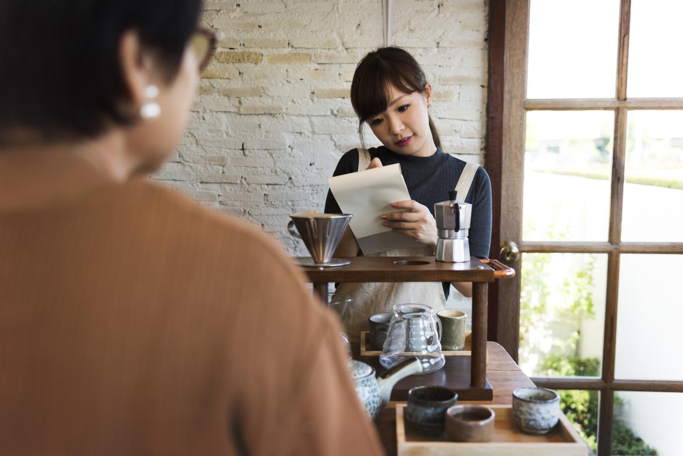 A scene in a coffee shop type environment with a waitress taking an order