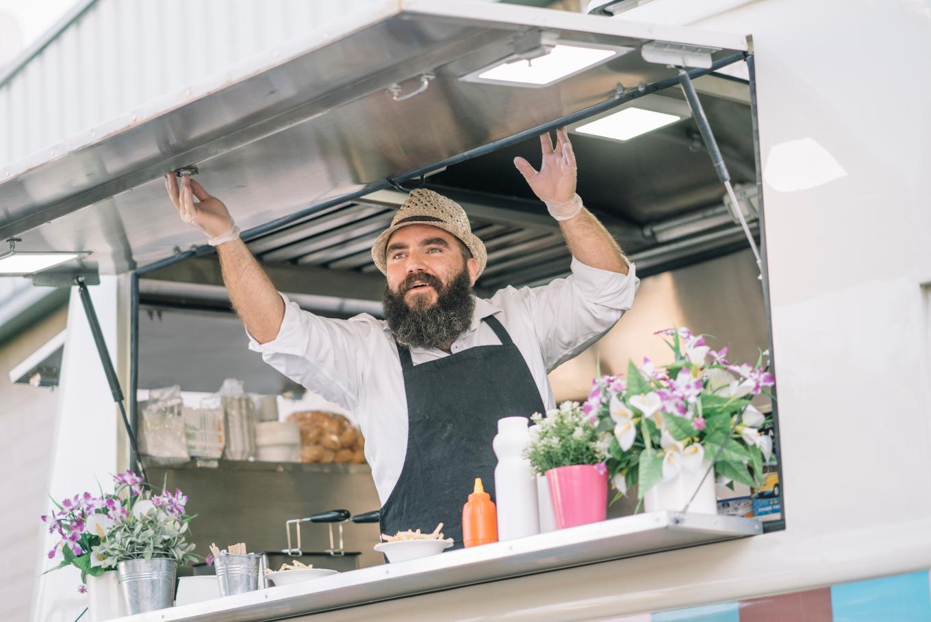 A male chef opening up the hatch of a food truck