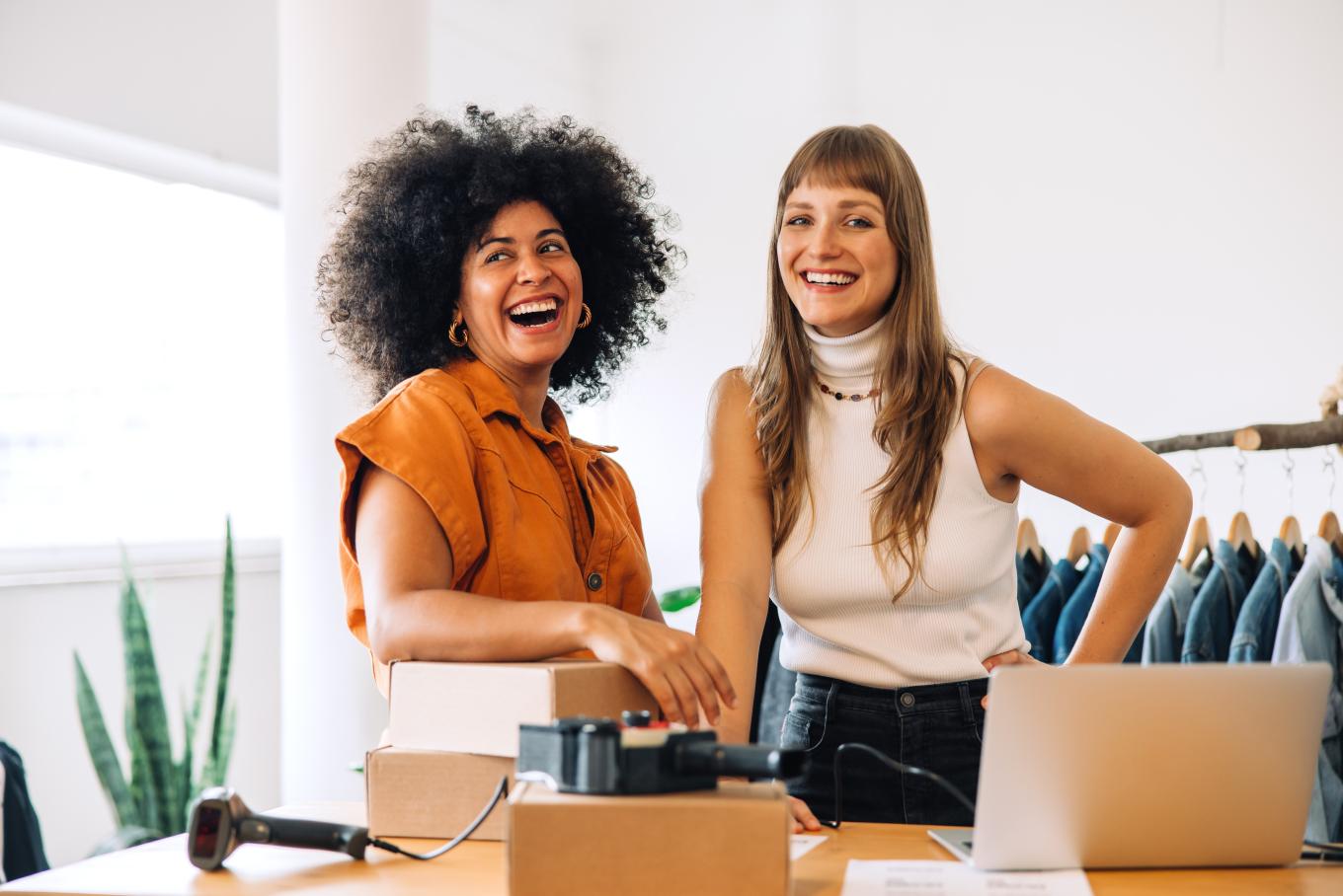 Two females, relaxed and smiling inside a clothing store environment
